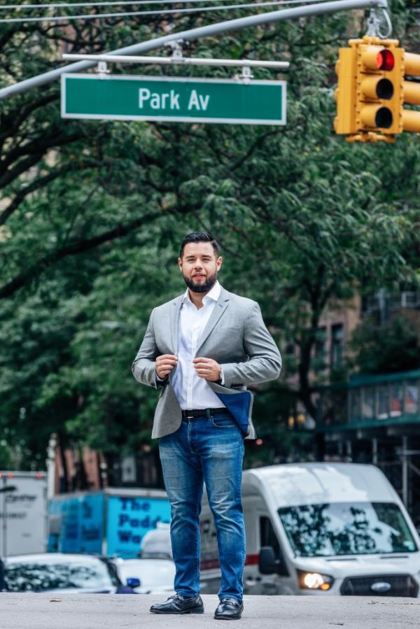 Stephen Bruno stands beneath a Park Avenue street sign wearing a jacket and jeans. 